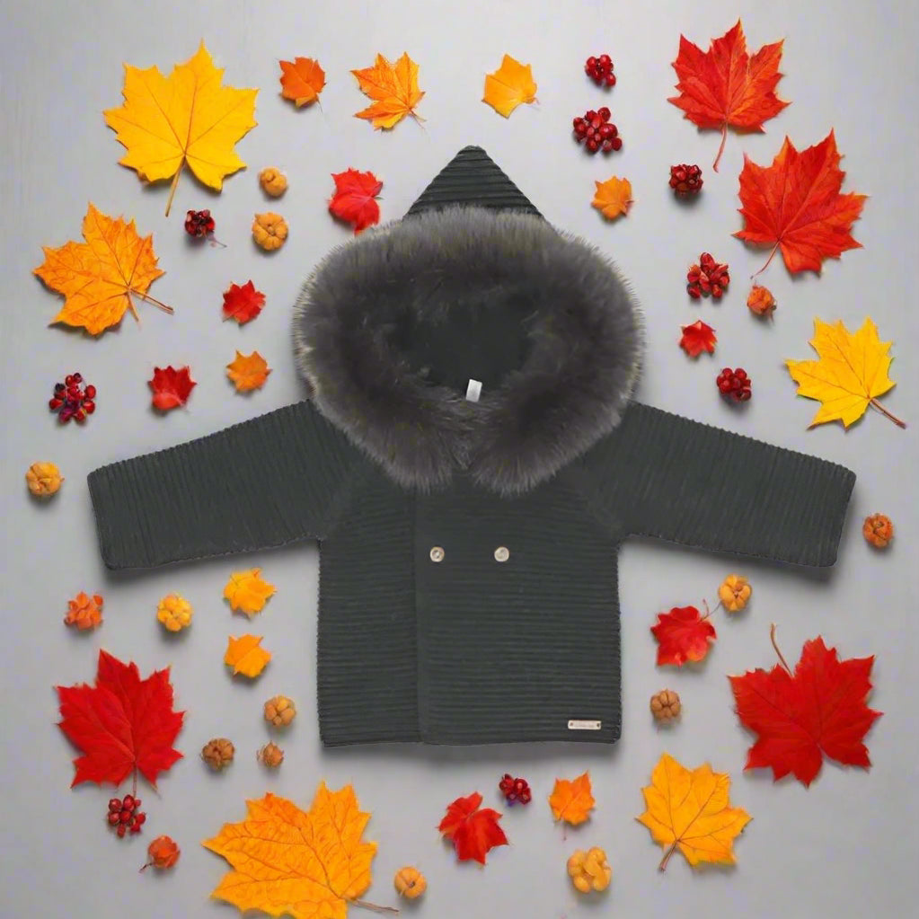 Dark gray knitted jacket with fur hood on a light gray background