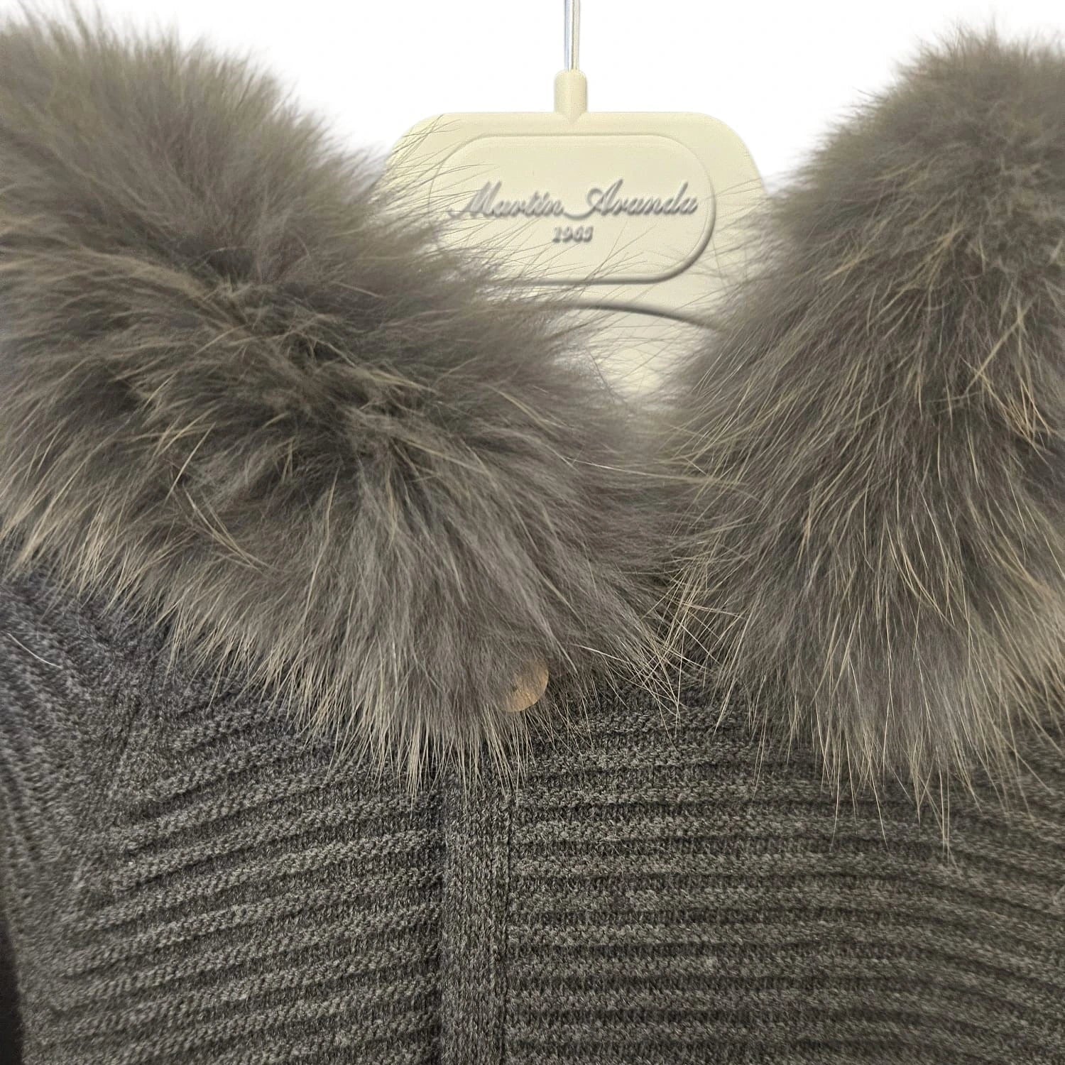 Gray knit cardigan with fur collar on a hanger