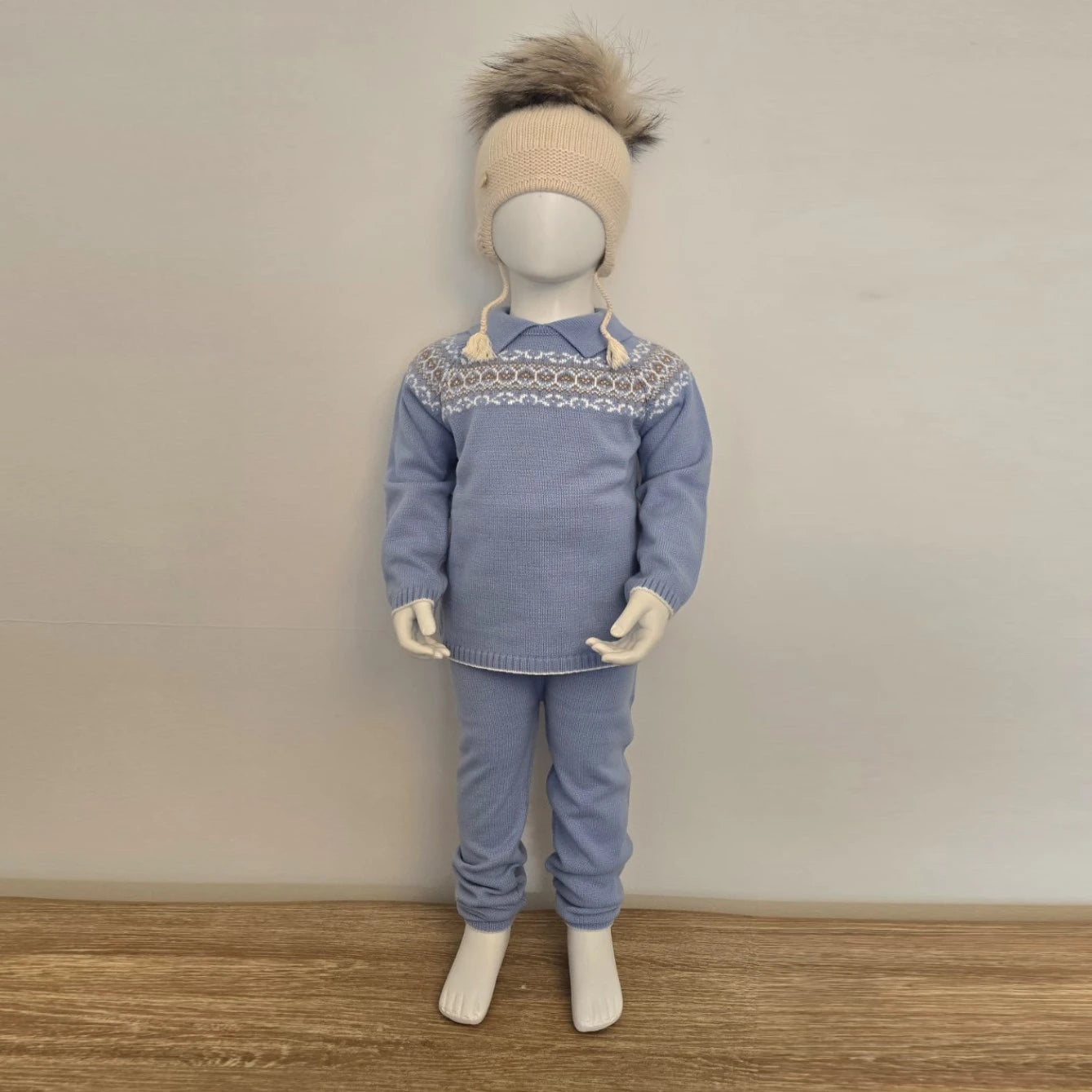 Mannequin wearing a blue sweater and pants set with a patterned collar against a plain background
