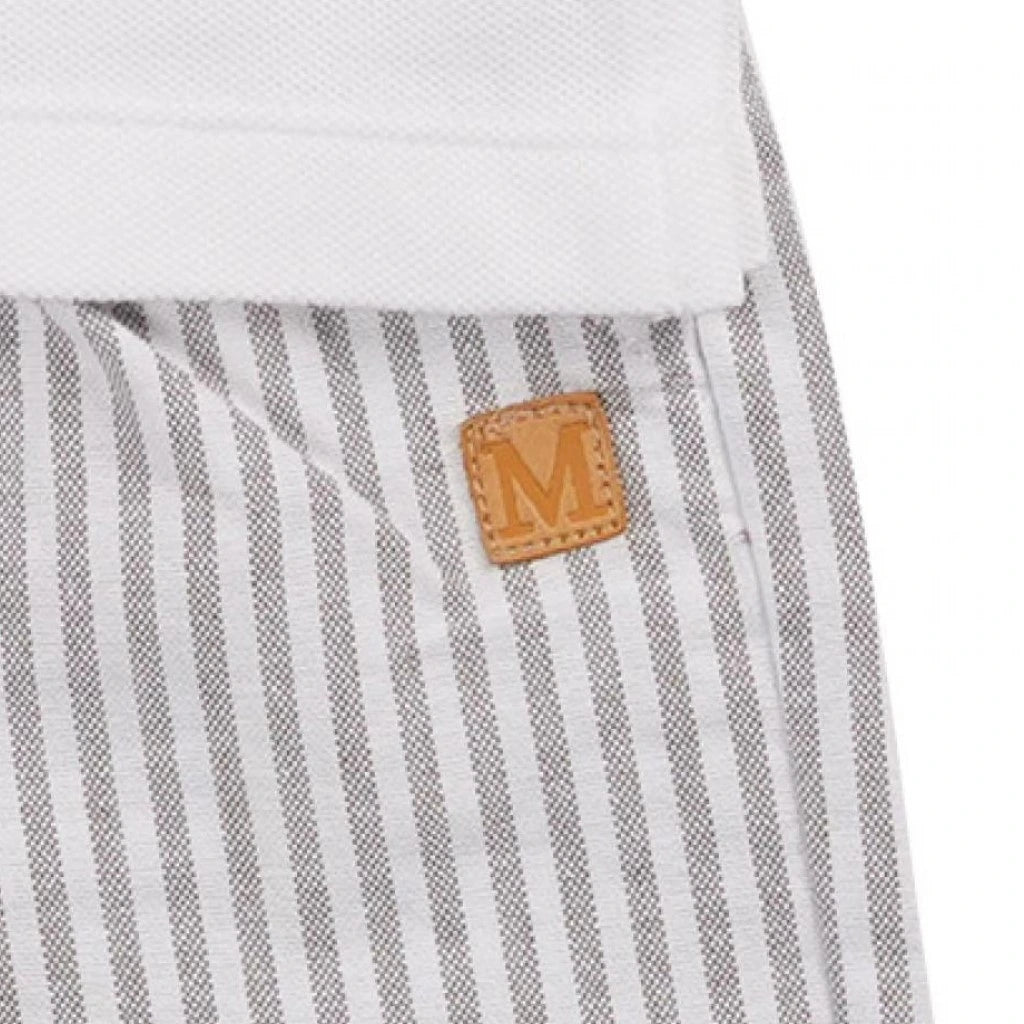A close-up of a beige and white striped shorts with a white polo shirt, featuring a leather tag with the letter 'M' on it.