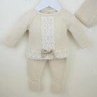 Beige baby outfit with lace details and a bow on a white background