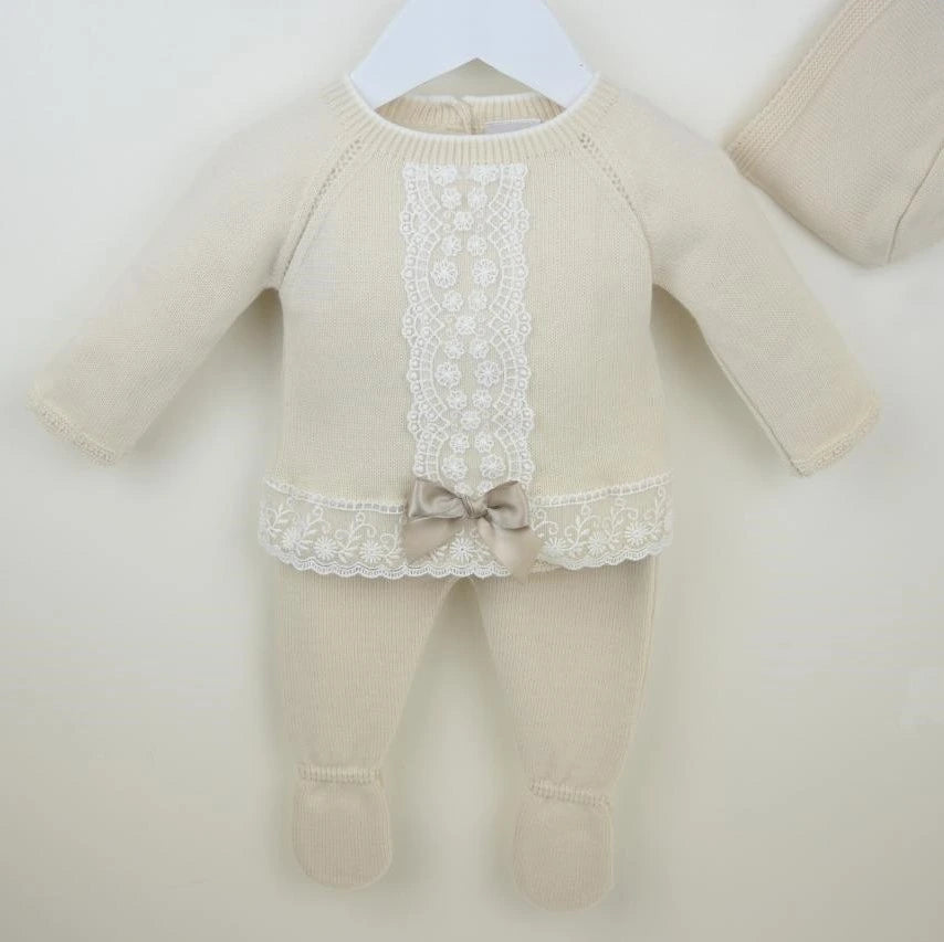 Beige baby outfit with lace details and a bow on a white background