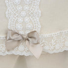 Close-up of beige fabric with white lace trim and a bow
