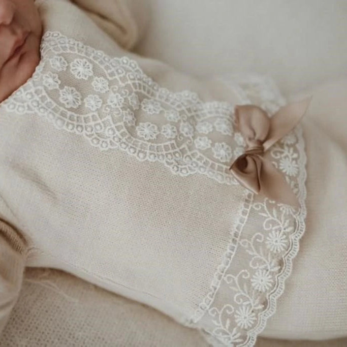 Baby wearing a beige outfit with lace details