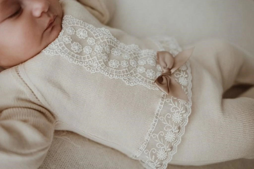 Baby wearing a beige outfit with lace details
