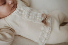 Baby wearing a beige outfit with lace details
