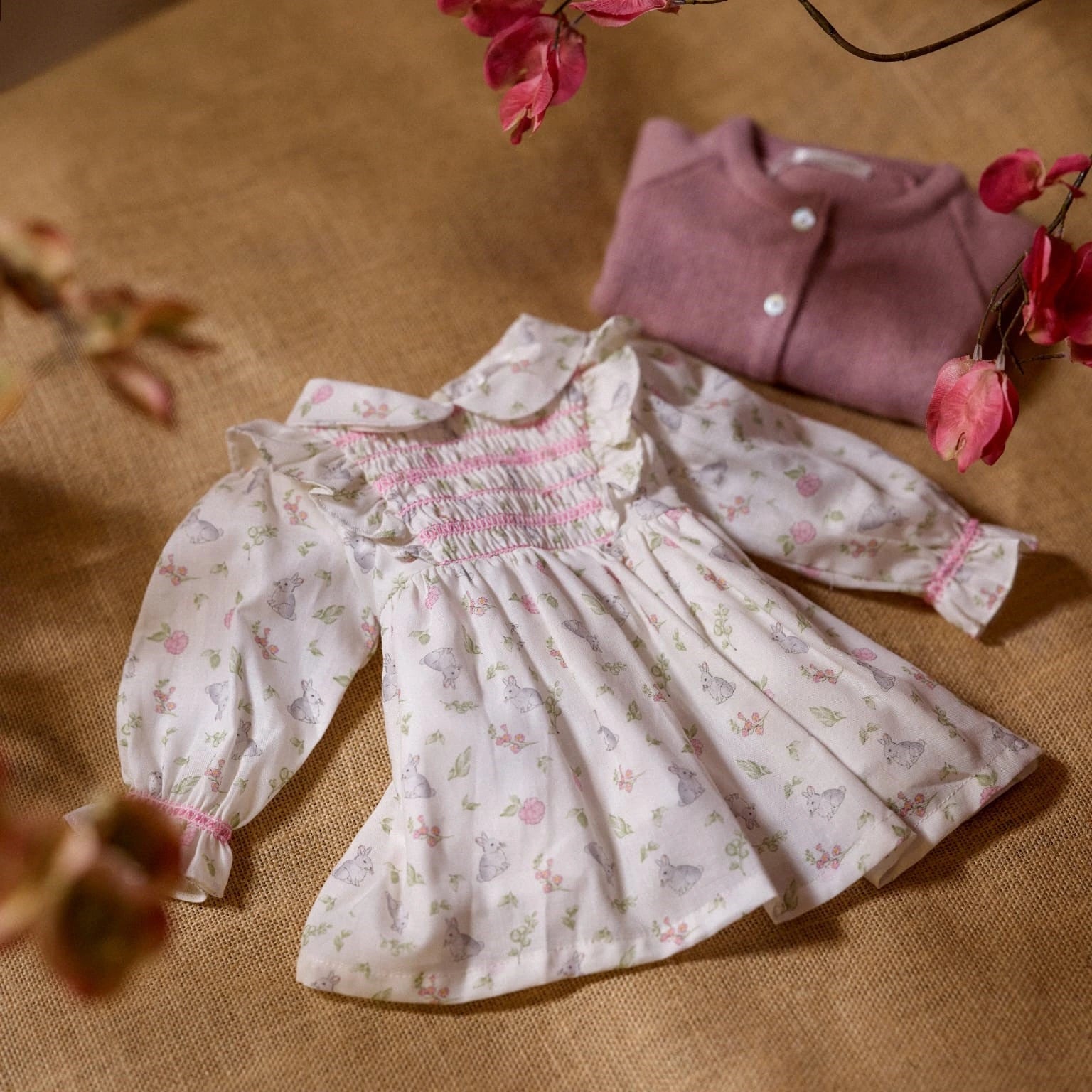 Floral dress with pink trim on a textured surface with flowers around