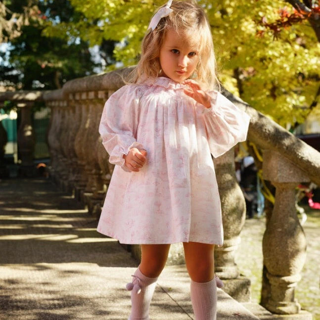 Young girl in a white dress standing outdoors with stone lanterns and trees in the background