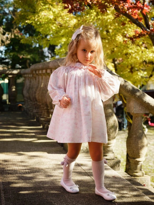Young girl in a white dress standing outdoors with stone lanterns and trees in the background