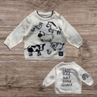 Children's sweaters with animal illustrations and text on a wooden surface