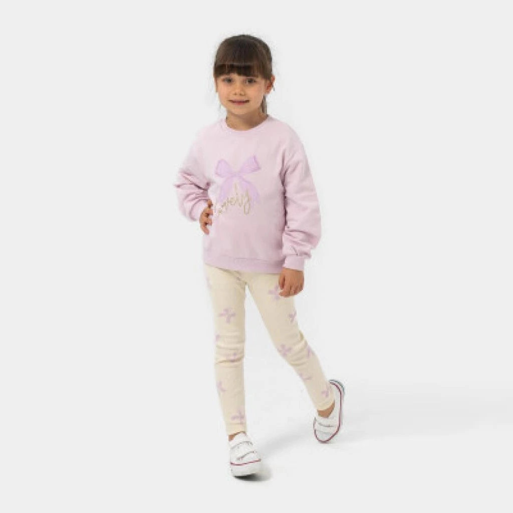 Young girl wearing a pink sweater with a bow design on a white background
