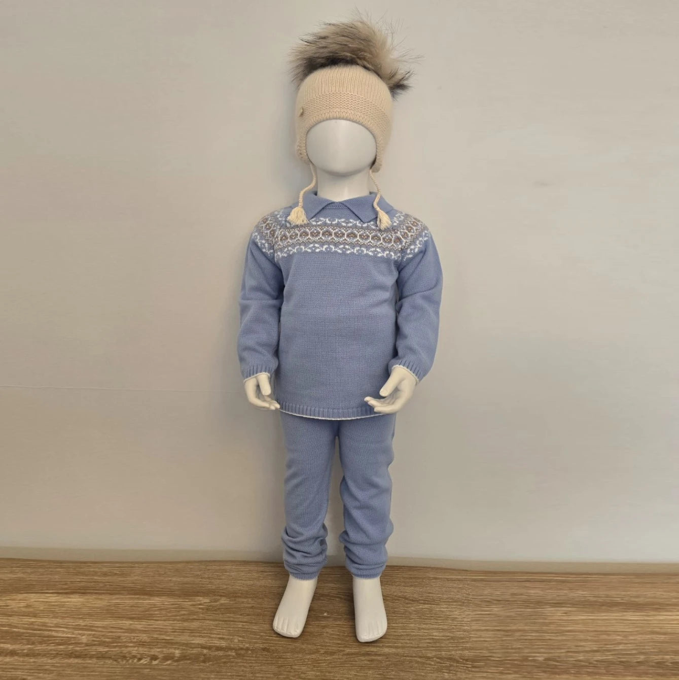 Mannequin wearing a blue sweater and pants set with a patterned collar against a plain background