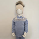 Mannequin wearing a blue sweater with a patterned collar and a beige knit hat on a plain background
