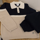 Black and beige striped sweater with buttons on a wooden surface