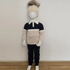 Mannequin wearing a sweater, pants, and hat on a plain background