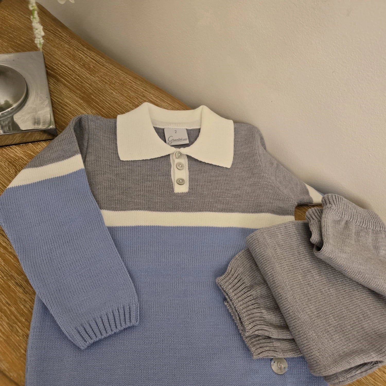Children's sweater and pants set on a wooden surface