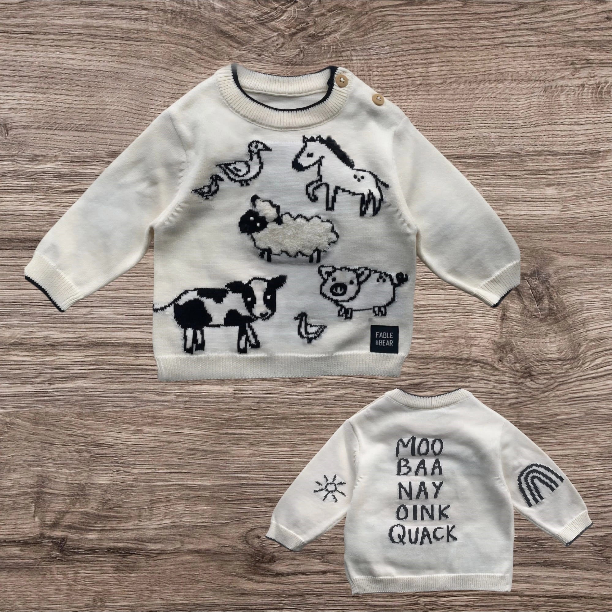 Children's sweaters with animal illustrations and text on a wooden surface