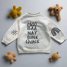 White sweater with text and graphics on a wooden floor
