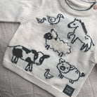 Children's sweater with farm animal designs on a textured surface