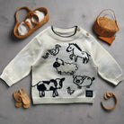 Children's sweater with farm animal patterns on a wooden floor