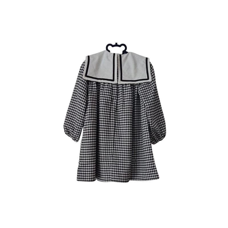 Black and white checkered dress on a hanger against a white background