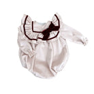 White baby romper with a brown bow on a white background