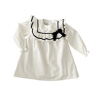 White dress with black ruffled collar and bow on a white background