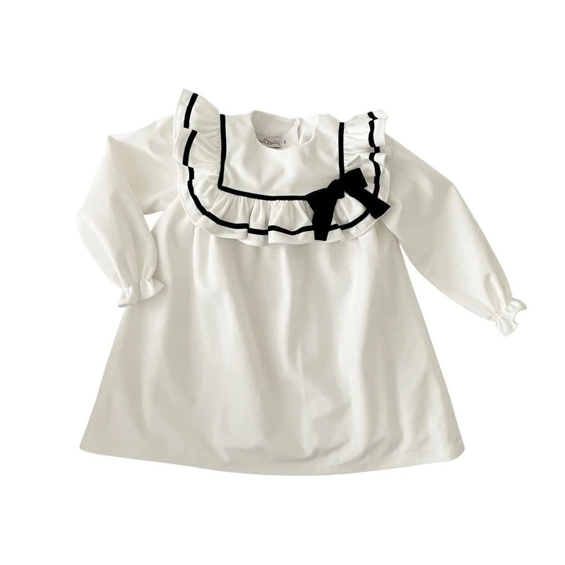 White dress with black ruffled collar and bow on a white background
