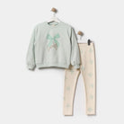Children's outfit with light green sweatshirt and beige leggings on a white background