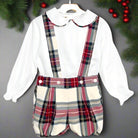 A boys' noel set consisting of a white woven shirt with red, green, and ivory tartan piping on the collar and matching tartan jam pants with braces.