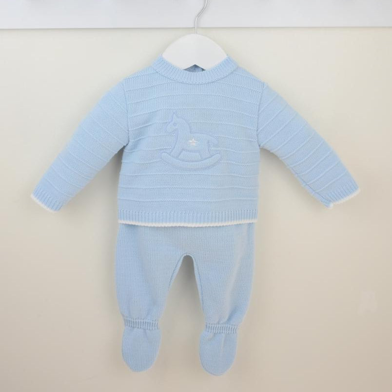 Light blue baby sweater and pants set hanging on a white hook against a beige wall.